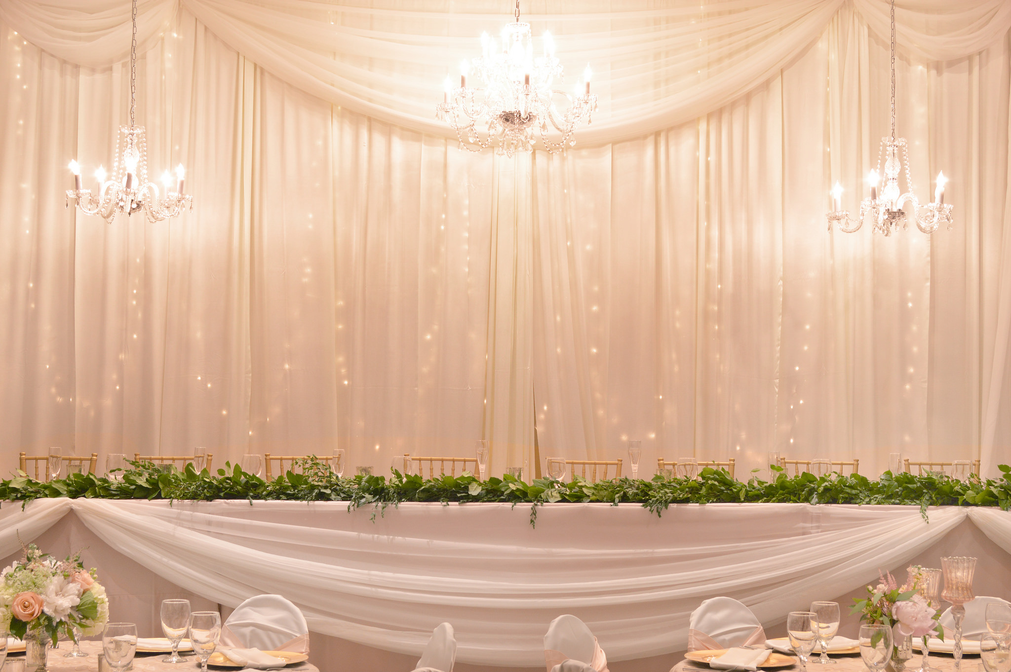 Chiffon panels are draped lengthwise on the front of this head table, then gathered at points to create swags.